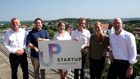 Präsentieren das neue Logo von Startup Osnabrück bei sommerlichem Wetter auf dem Balkon des Osnabrücker Stadthauses (vlnr.): Ralf Minning (WFO), Niklas Schwichtenberg (Aloys & Brigitte Coppenrath Stiftung), Prof. Dr. Karin Schnitker (Hochschule Osnabrück), Lars Brendler (WFO), Annika Hörnschemeyer (HWK) und Frank Hesse (IHK).